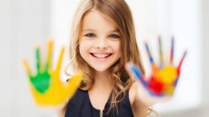 education, school, art and painitng concept - smiling little student girl showing painted hands at school